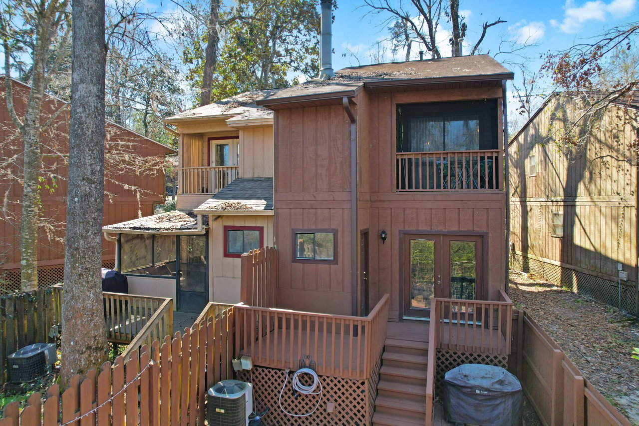 Two-story brown wooden house with balconies, surrounded by a wooden fence and trees. The setting feels tranquil and secluded, under a blue sky.Two-story brown wooden house with balconies, surrounded by a wooden fence and trees. The setting feels tranquil and secluded, under a blue sky.