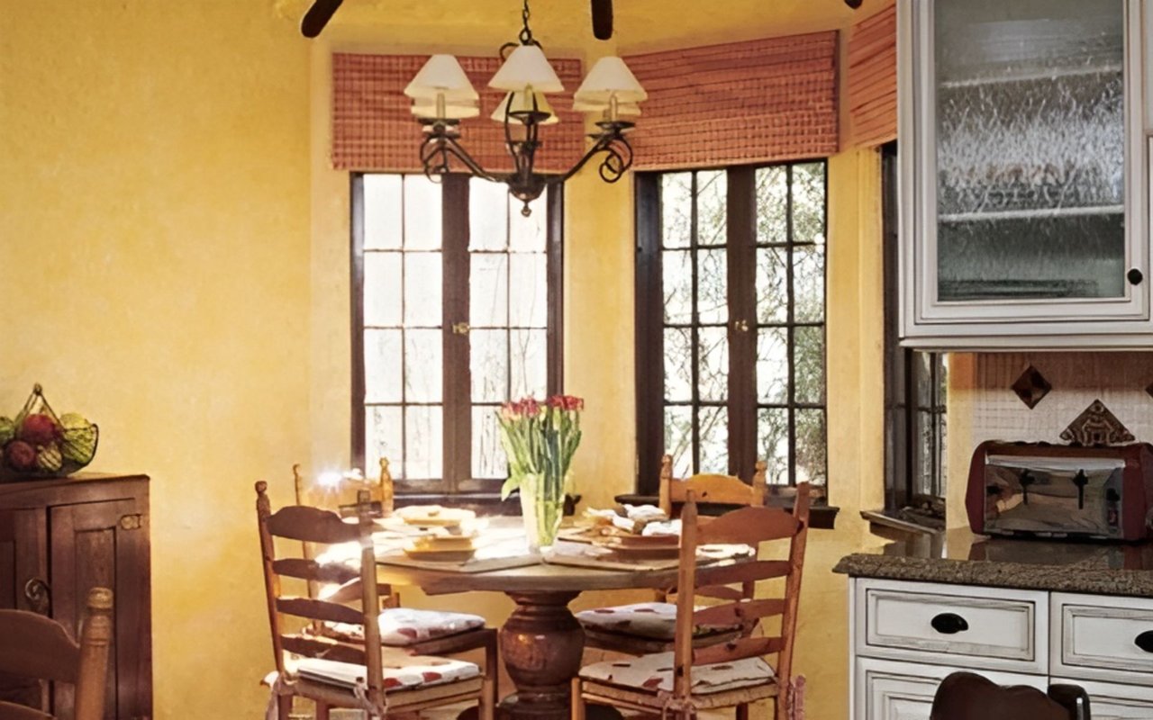 Dining area with a set wooden table, tall divided-light windows, and a chandelier.
