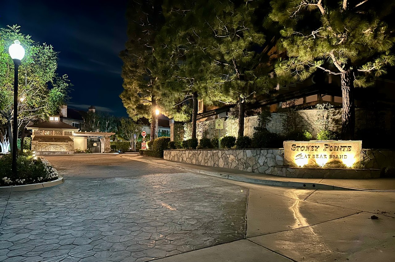 Stoney Pointe at Bear Brand entry in Laguna Niguel — illuminated stone wall signage community entrance with pine trees
