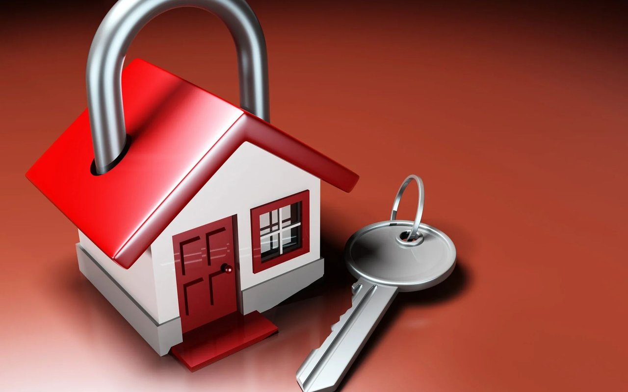 A red-roofed house secured by a large padlock, beside a key.