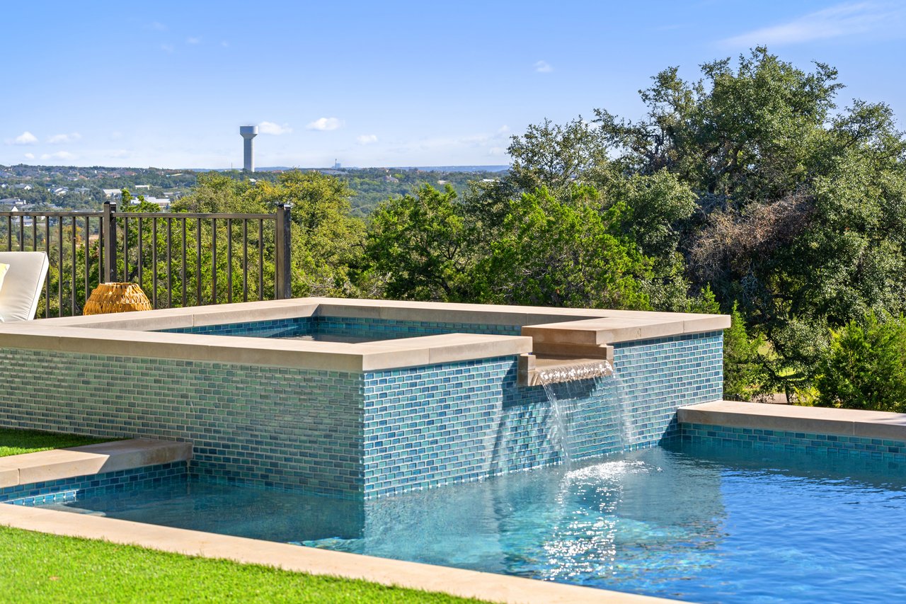 Pool and raised spa with a waterfall spillover, overlooking the downtown Austin skyline from this Caudill Lane home in the Bee Caves area.