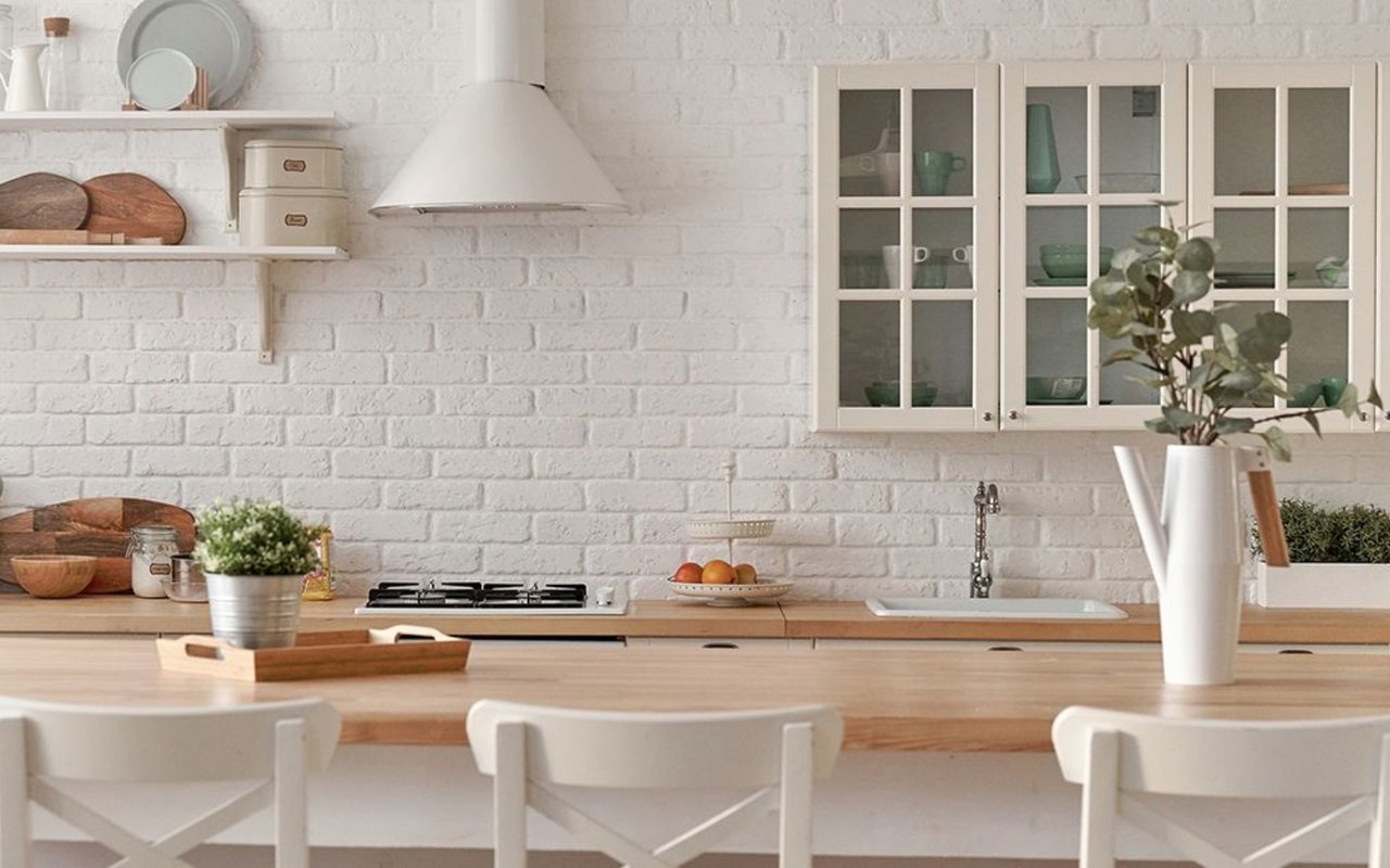 Bright kitchen with a white brick backsplash, glass-front cabinets, and a broad wood island.
