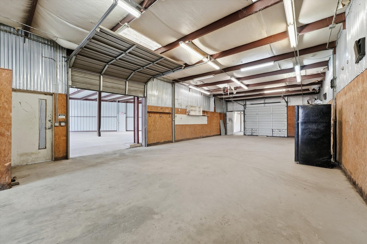 Vacant industrial garage with corrugated metal walls, exposed beams, and a large concrete floor.