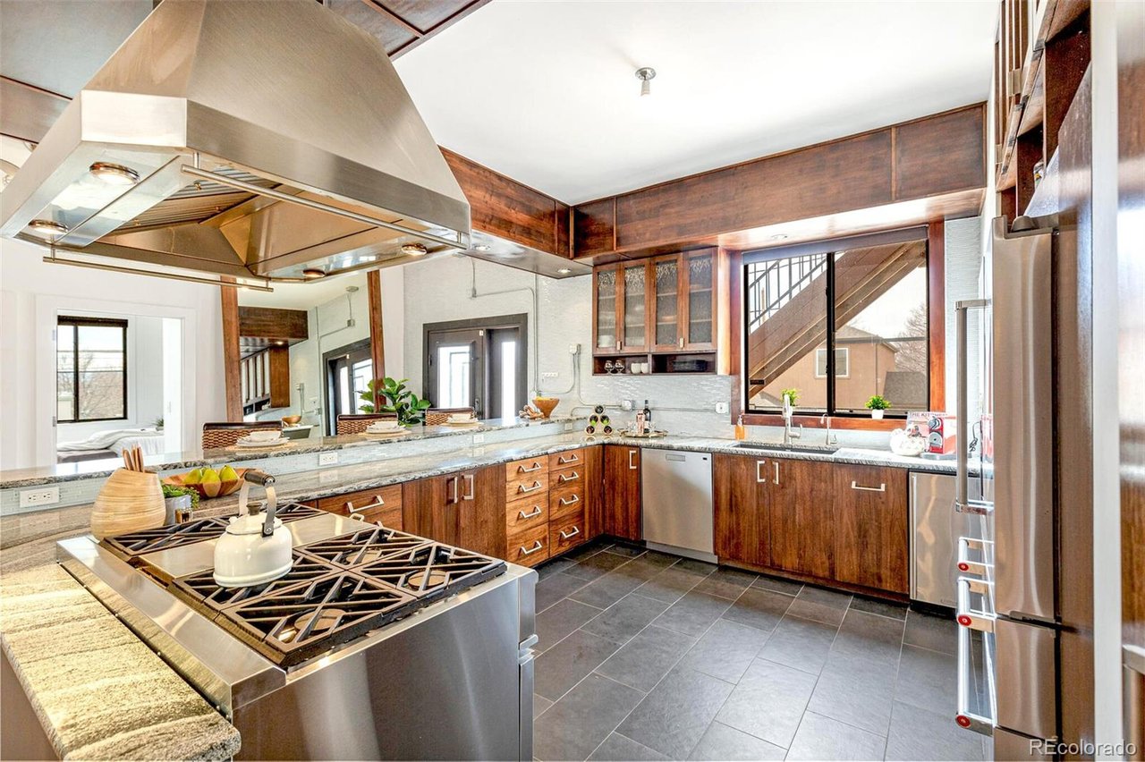 Kitchen with dark wood cabinets, granite counters, stainless steel appliances, and a large range hood.