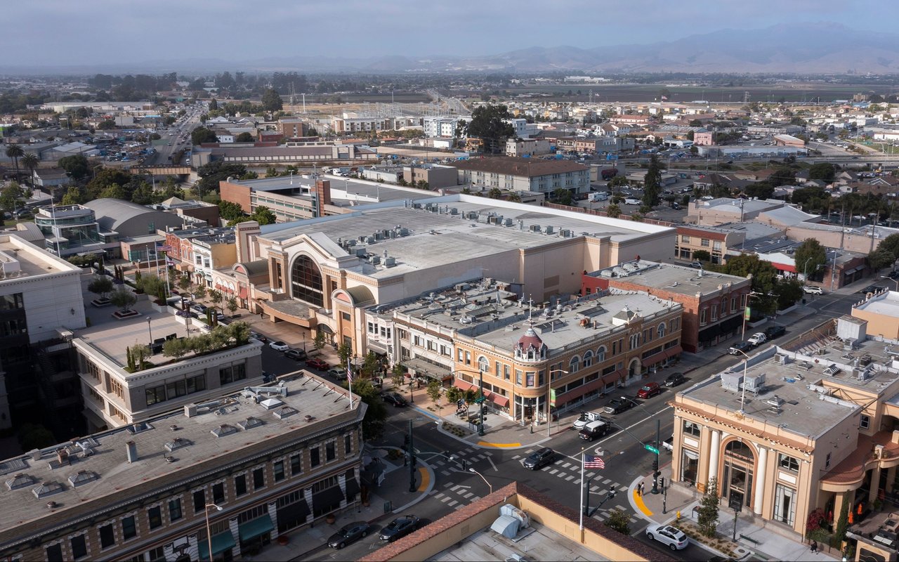 Aerial view of downtown Salinas, with commercial blocks, surrounding farmland, and distant mountains.
