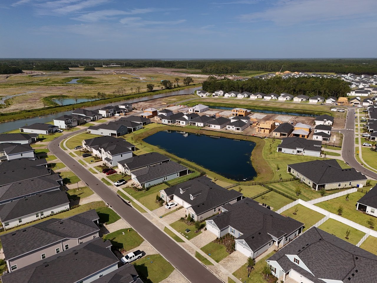 Aerial view of homes around a pond, with several houses under construction.