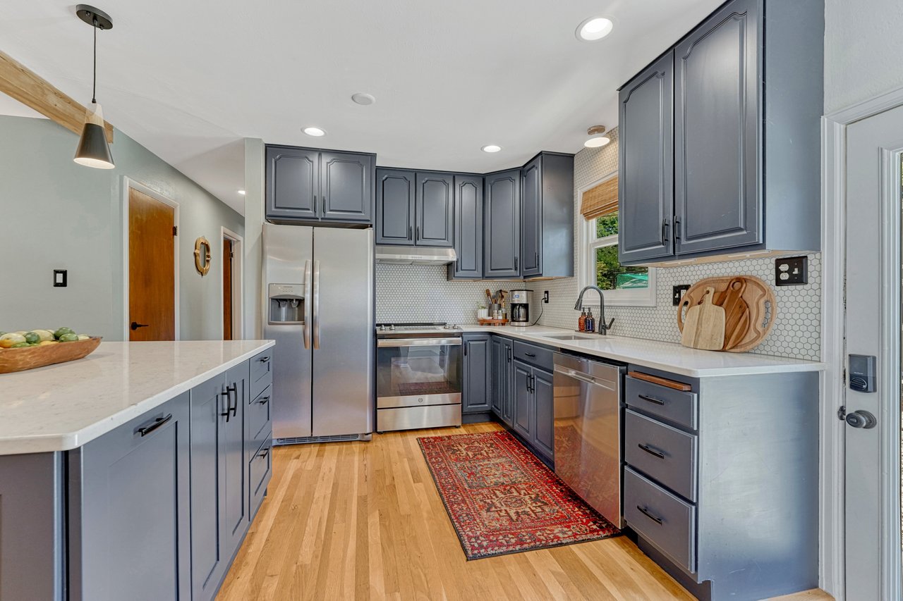 Kitchen with gray cabinets, white hex tile backsplash and a stainless refrigerator, range and dishwasher