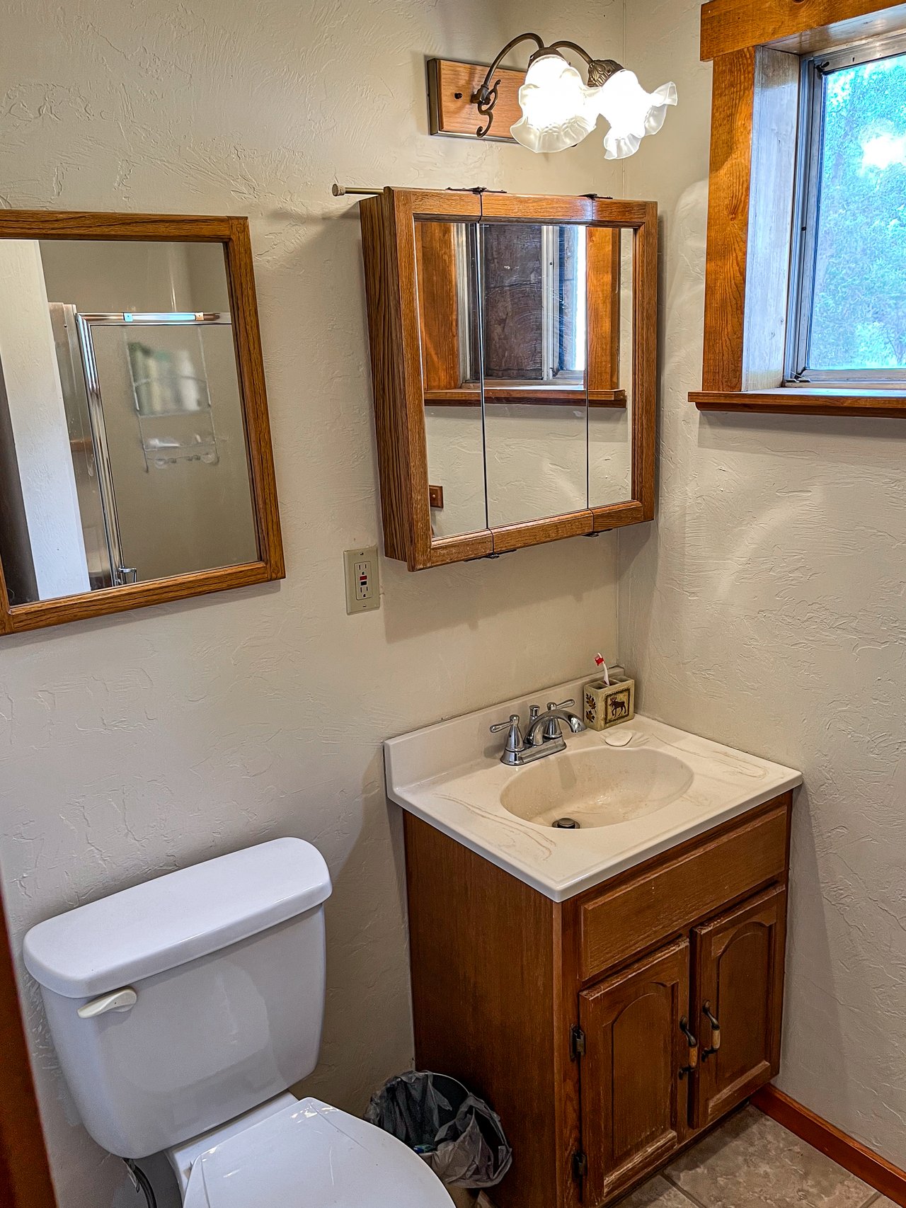 Bathroom with a wooden vanity, mirrored medicine cabinet, white sink, and toilet.