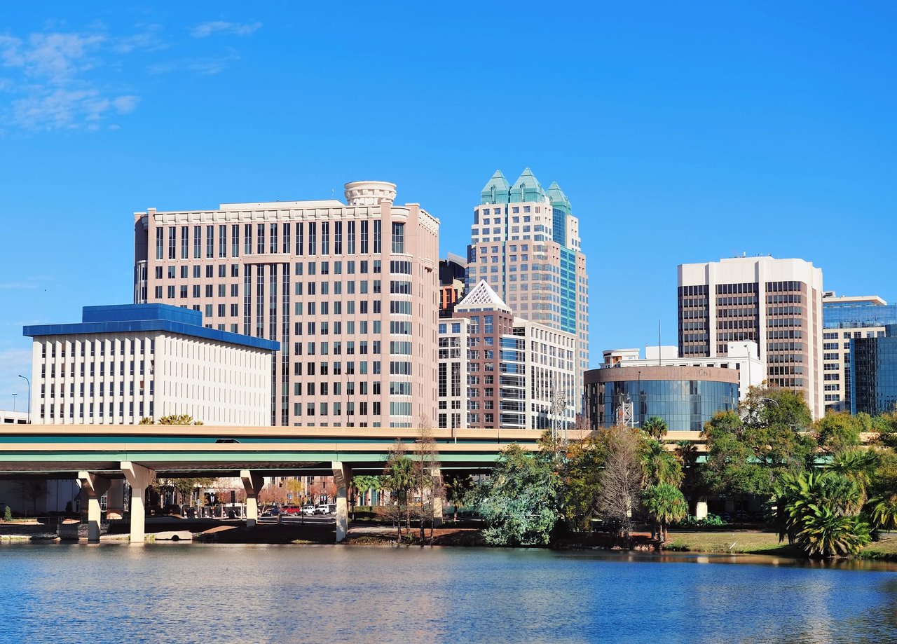 Downtown Orlando buildings across the water, with an elevated roadway in the foreground.