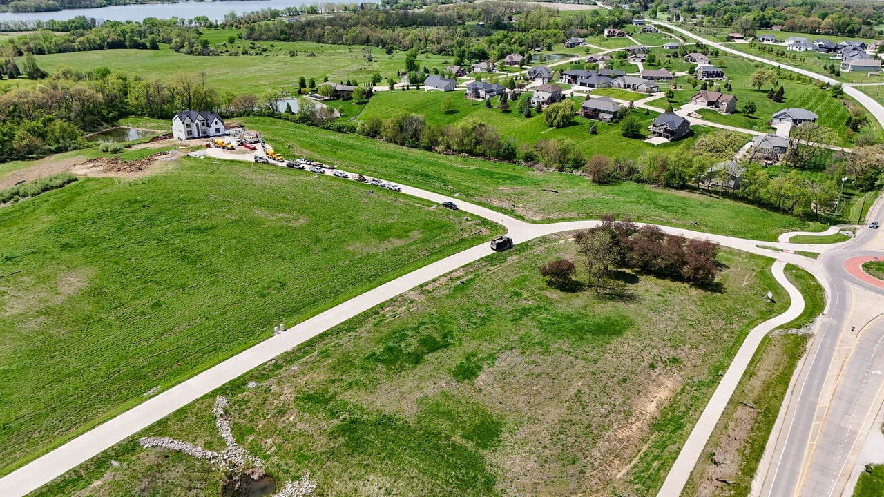 Oak Meadow development with scattered homes, open lots, curving roads, and a river in the distance.