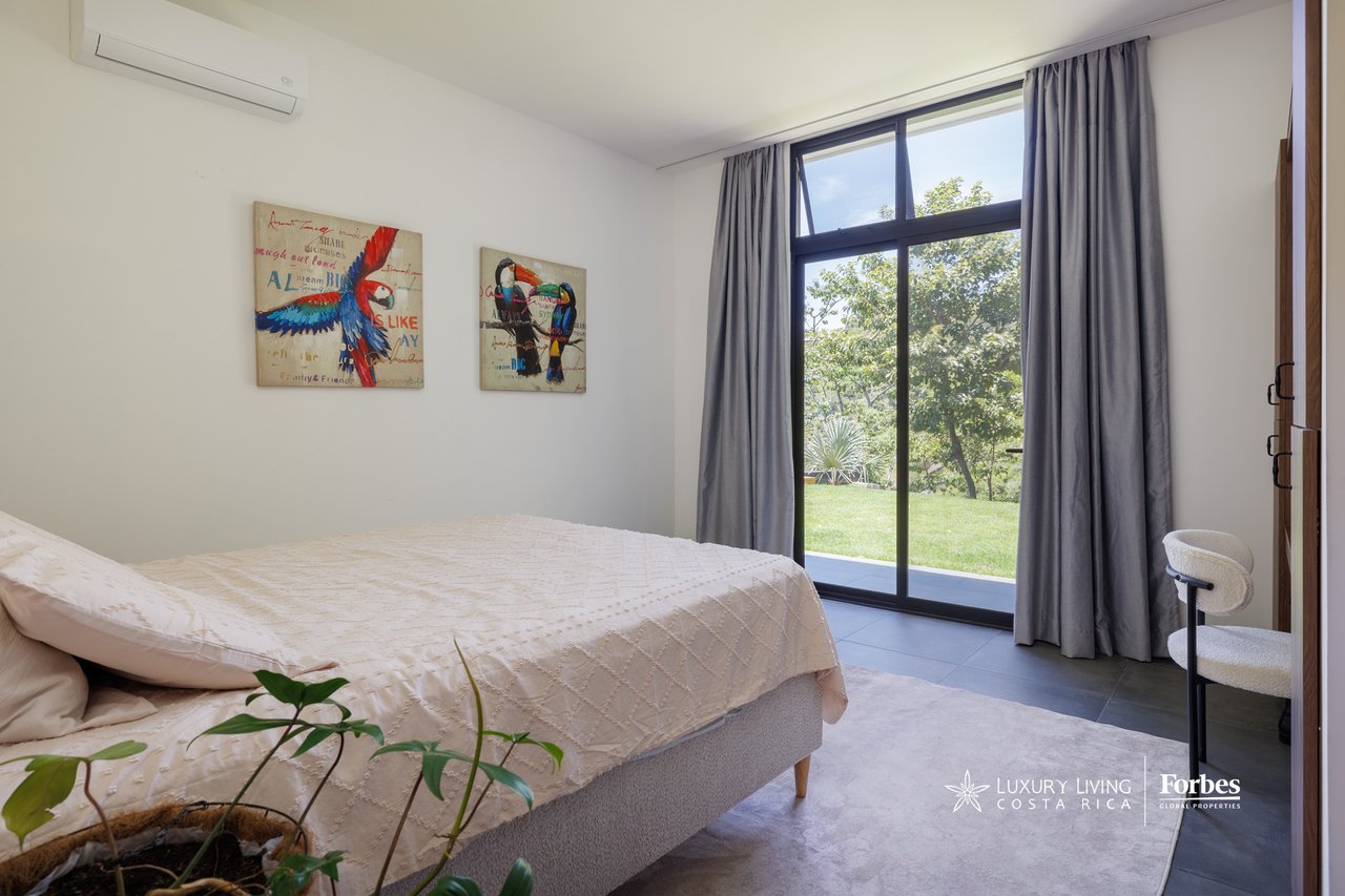 Bedroom with a cream bed and glass doors overlooking a garden.