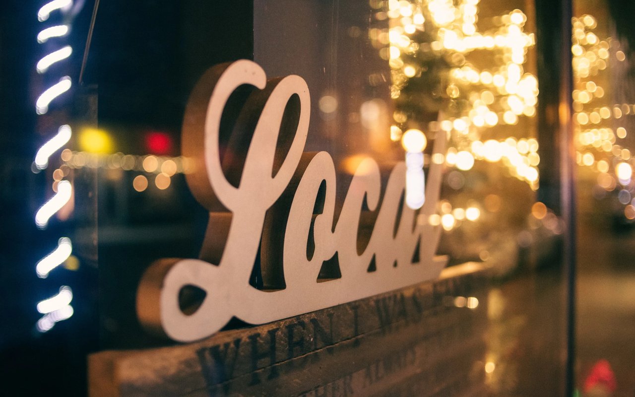 A blurry, low-light shot of a wooden sign on a window with bokeh lights in the background.