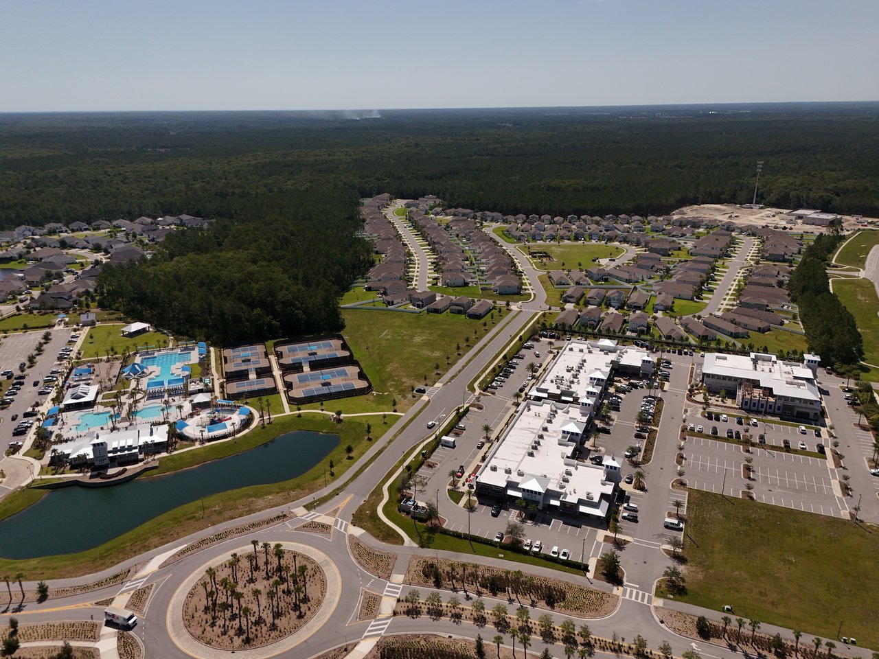 Aerial view of homes and community amenities, including pools, tennis courts, and a pond.