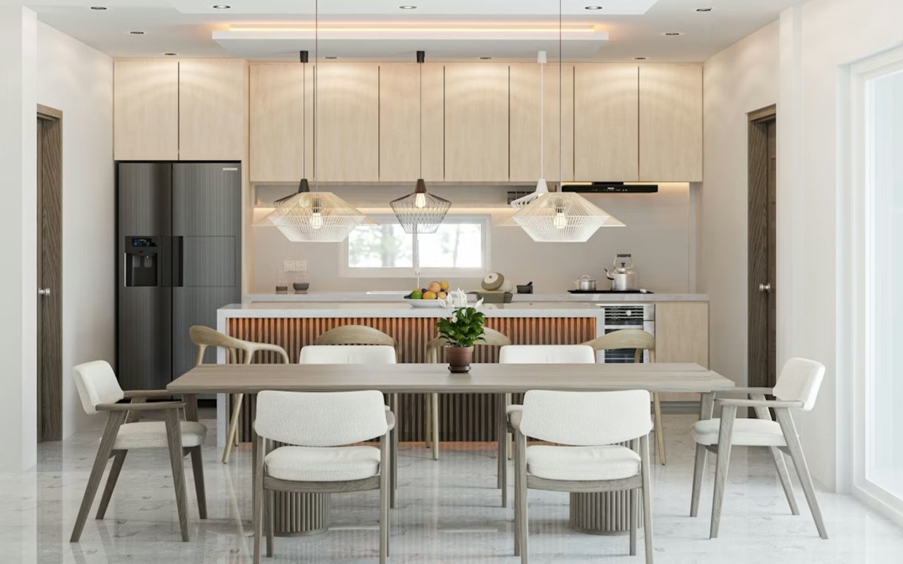 Modern kitchen and dining area with light wood cabinetry and a long table beneath pendant lights.