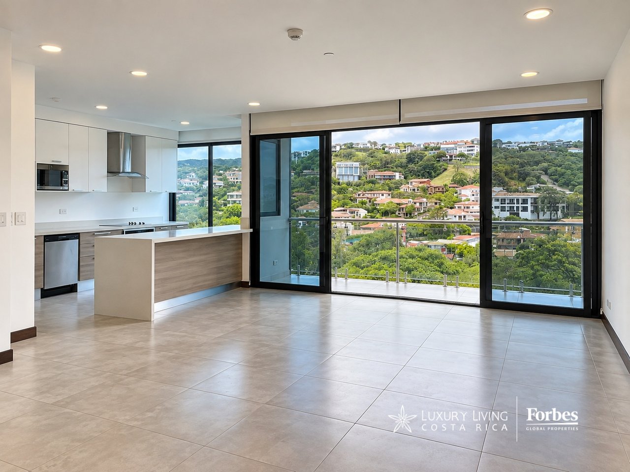 Unfurnished apartment kitchen and living area with floor-to-ceiling windows overlooking a green hillside neighborhood.