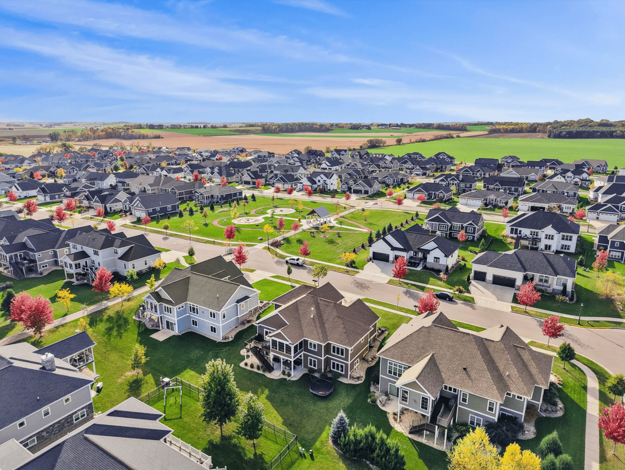 An expansive aerial view of a modern, high-end residential neighborhood in Waunakee, Wisconsin, featuring contemporary homes and green spaces, illustrating the 2026 inventory surge and new construction competition.
