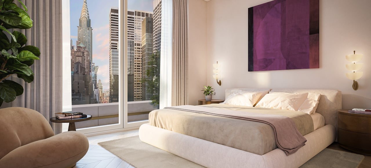 Staged bedroom with a cream bed and Manhattan skyline views through floor-to-ceiling windows.