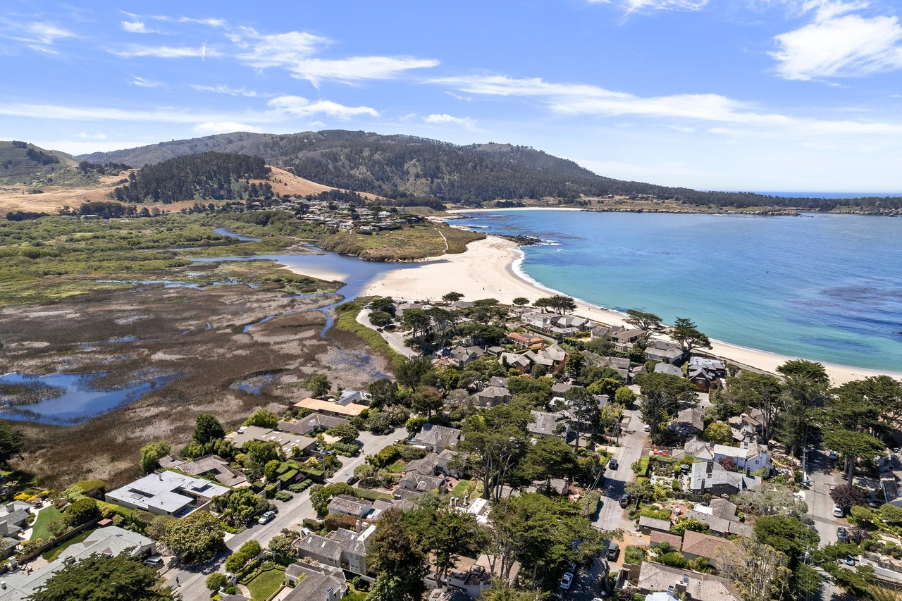 Aerial view of Carmel Point homes along Carmel Beach, with turquoise ocean, cypress trees, and golf course in the distance.