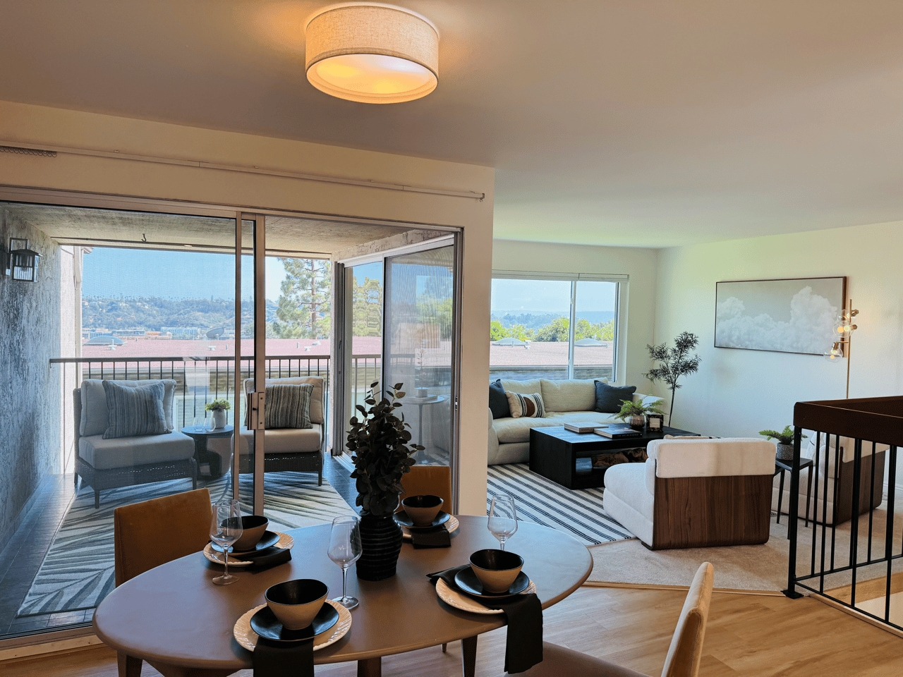 Stylish dining area and living room at 6321 Caminito Luisito, San Diego CA 92111, featuring a private balcony with seating, panoramic hillside views, modern furniture, and natural light-filled open layout.