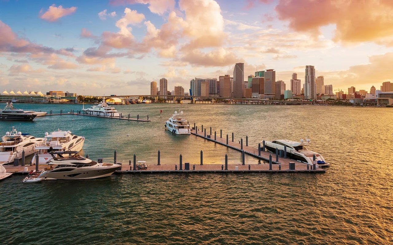 Miami skyline and waterfront with moored yachts at golden hour.