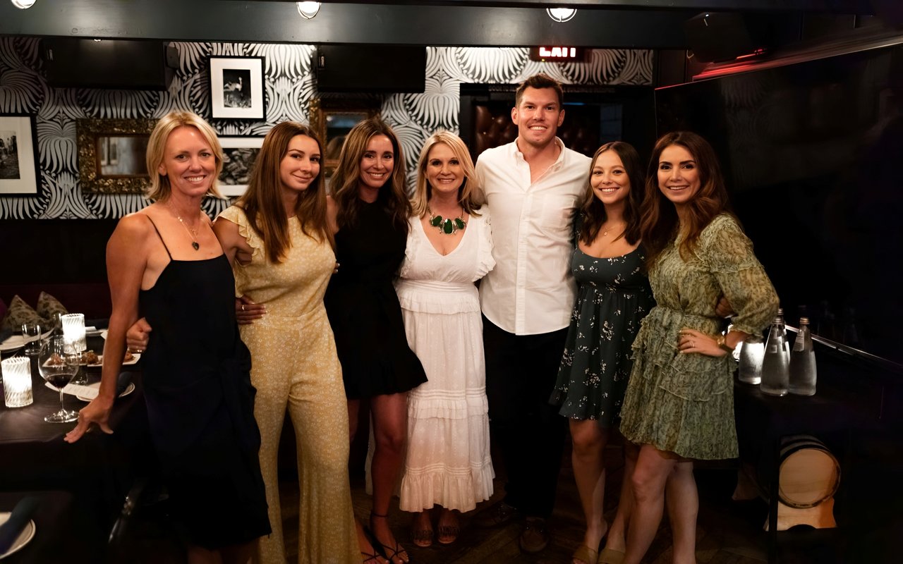 A real estate team, including five women and one man, posing for a photo in a dimly lit restaurant or bar.