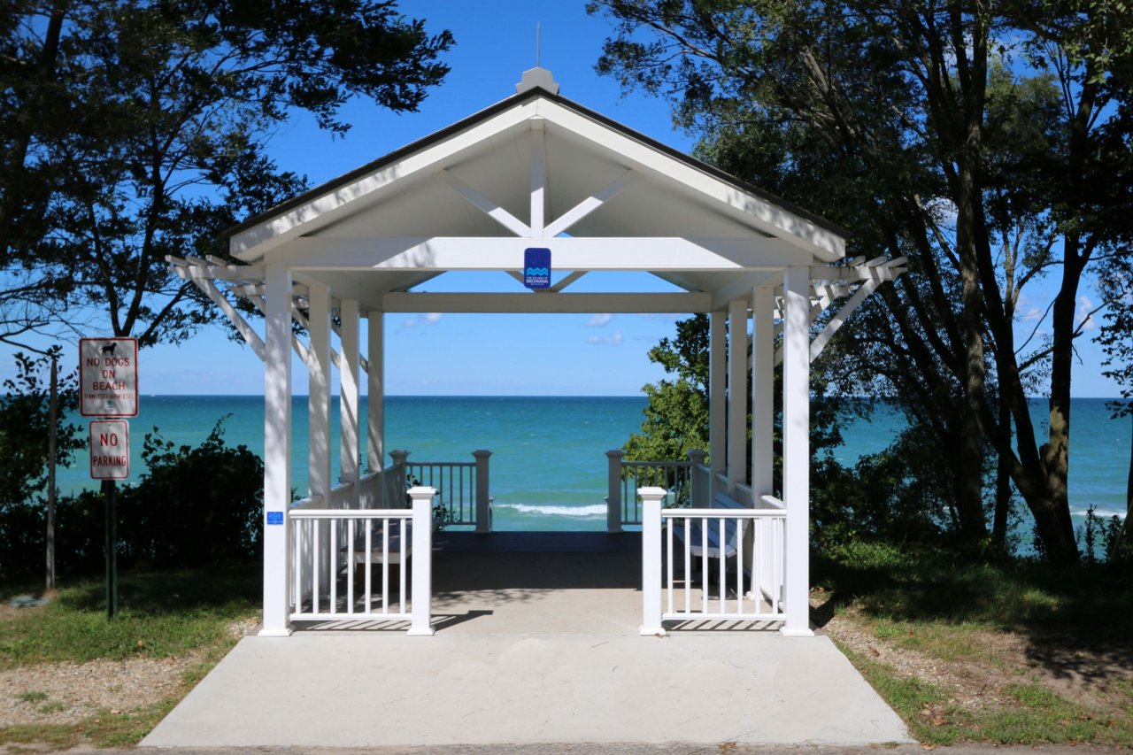 White beach pavilion overlooking Lake Michigan, with no-dogs and no-parking signs at the entrance.