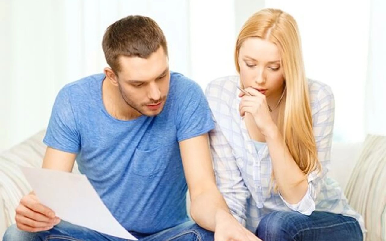 A couple reviews a document together on a sofa.