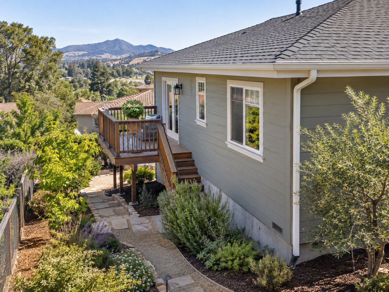 Multiple exterior building materials, roof transitions, eaves, deck surfaces, and mature landscaping show the different areas a homeowner must maintain over time.