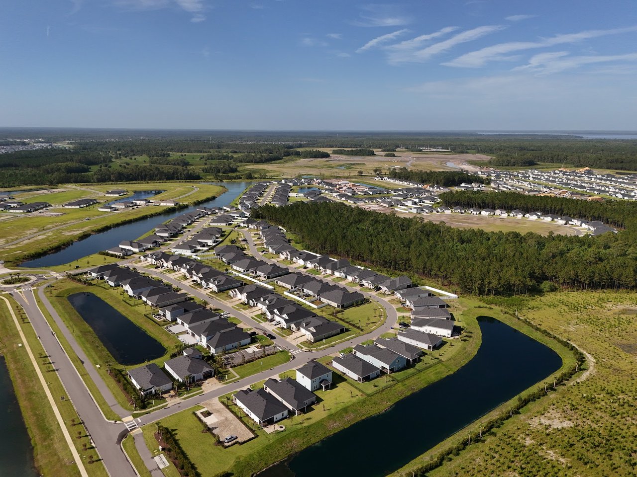 Aerial view of a neighborhood with detached homes, curving streets, and surrounding waterways.