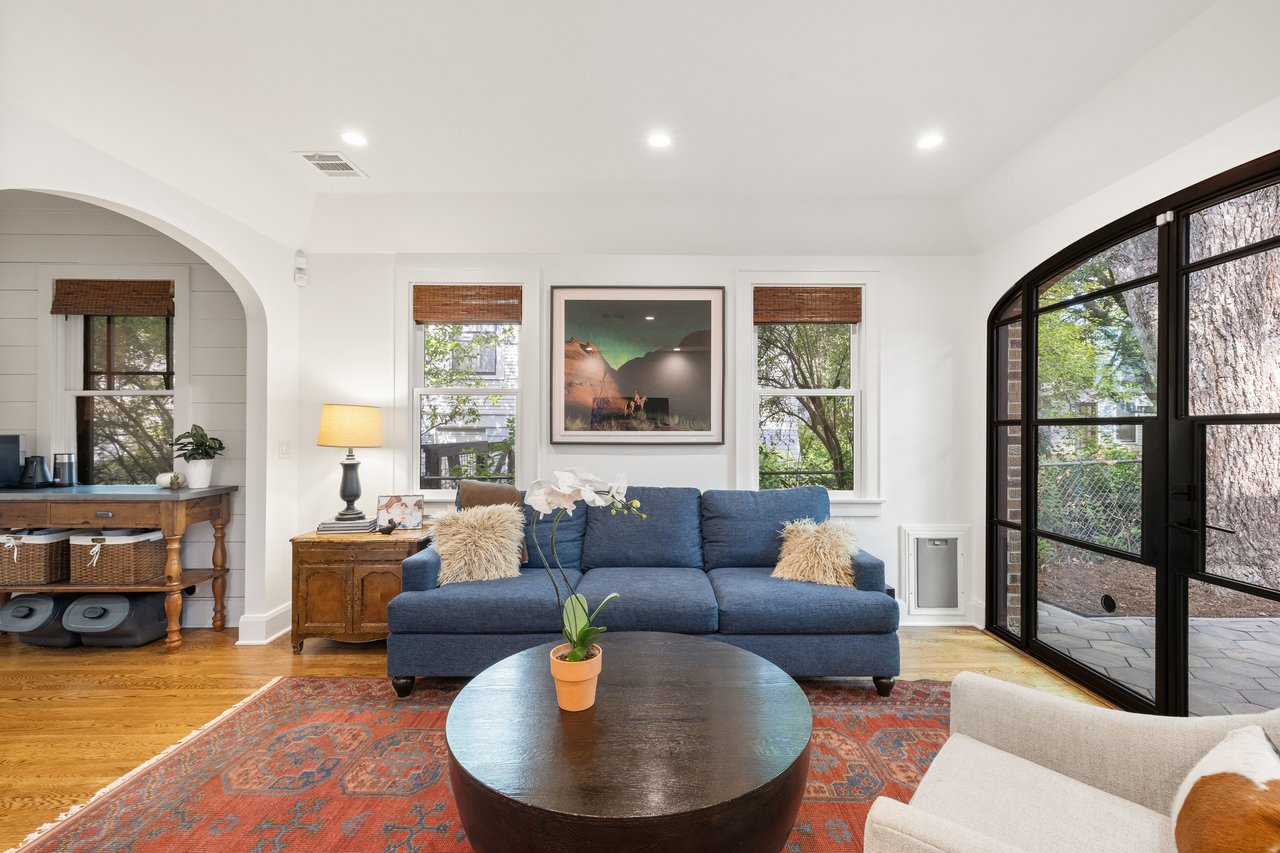 Living room with a blue sofa, patterned rug, and arched black-framed glass doors.