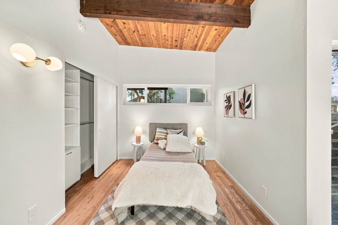 Staged bedroom with a wood-plank ceiling, built-in shelving, and a single bed.