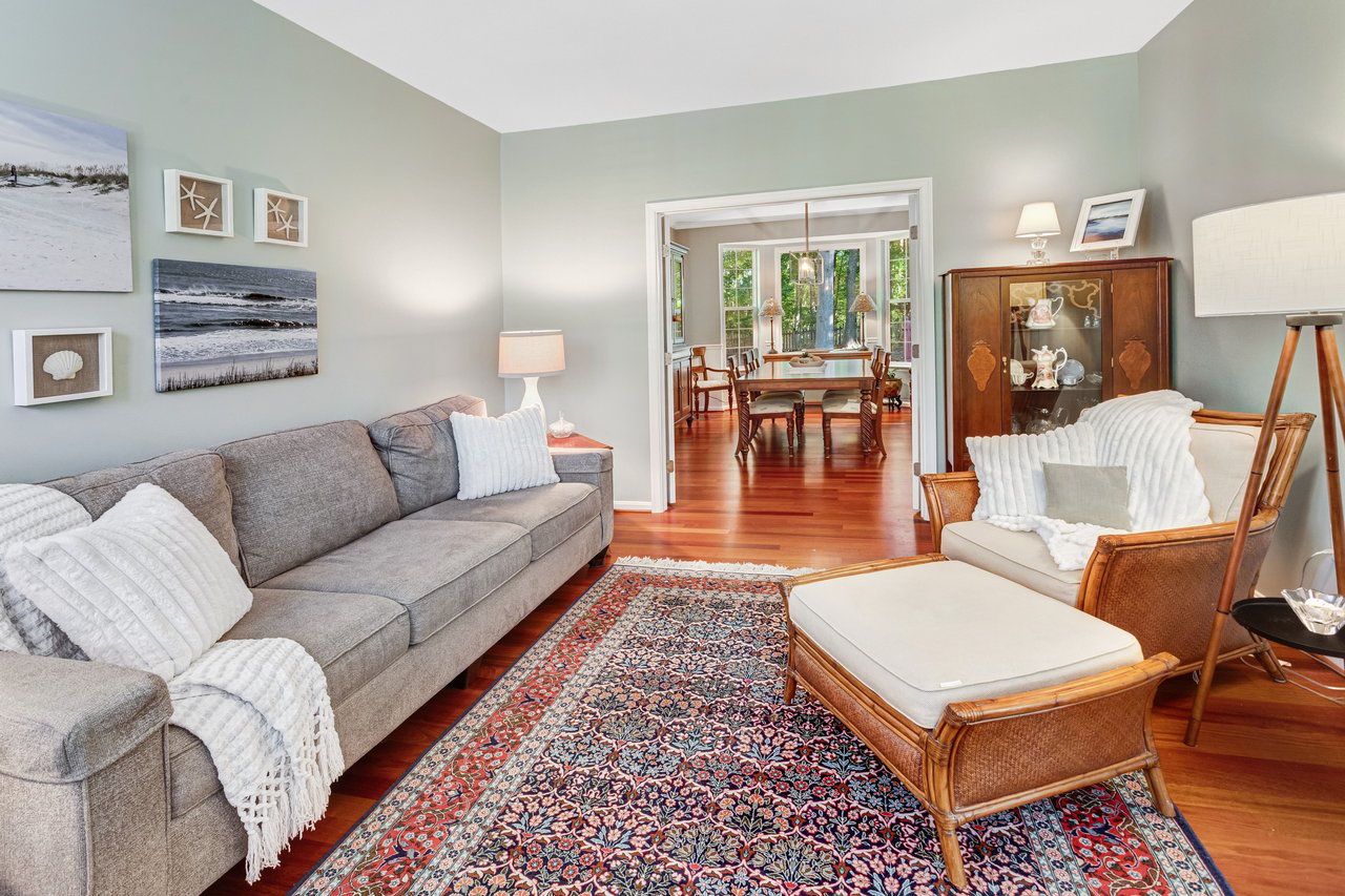 Living room with gray sectional, patterned rug, and a view into the dining room.