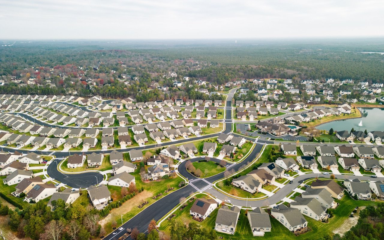 Aerial view of a suburban neighborhood with curving streets, detached homes, and a pond.