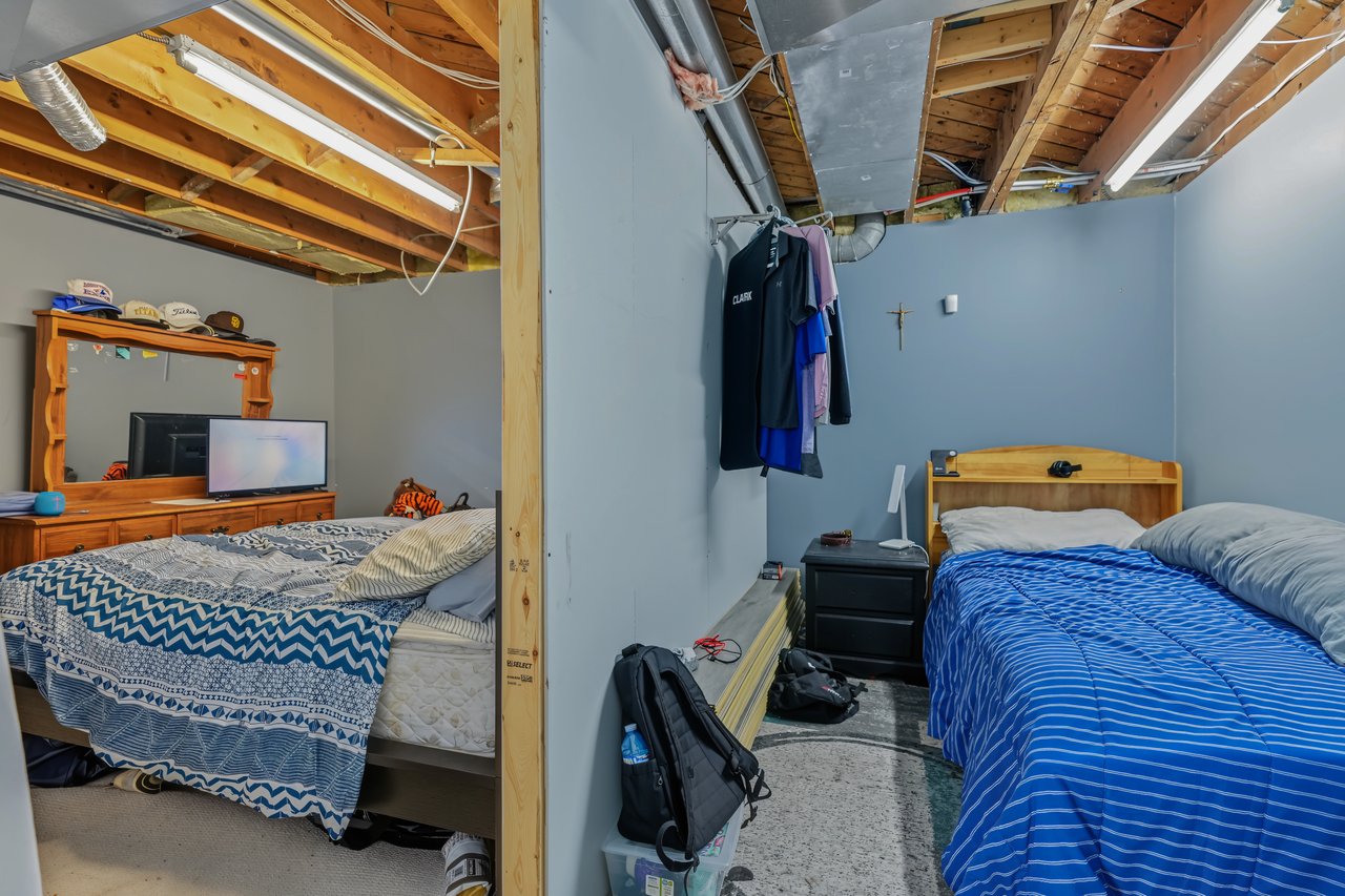 Two furnished bedrooms with exposed ceiling joists and beds on either side of a partition.