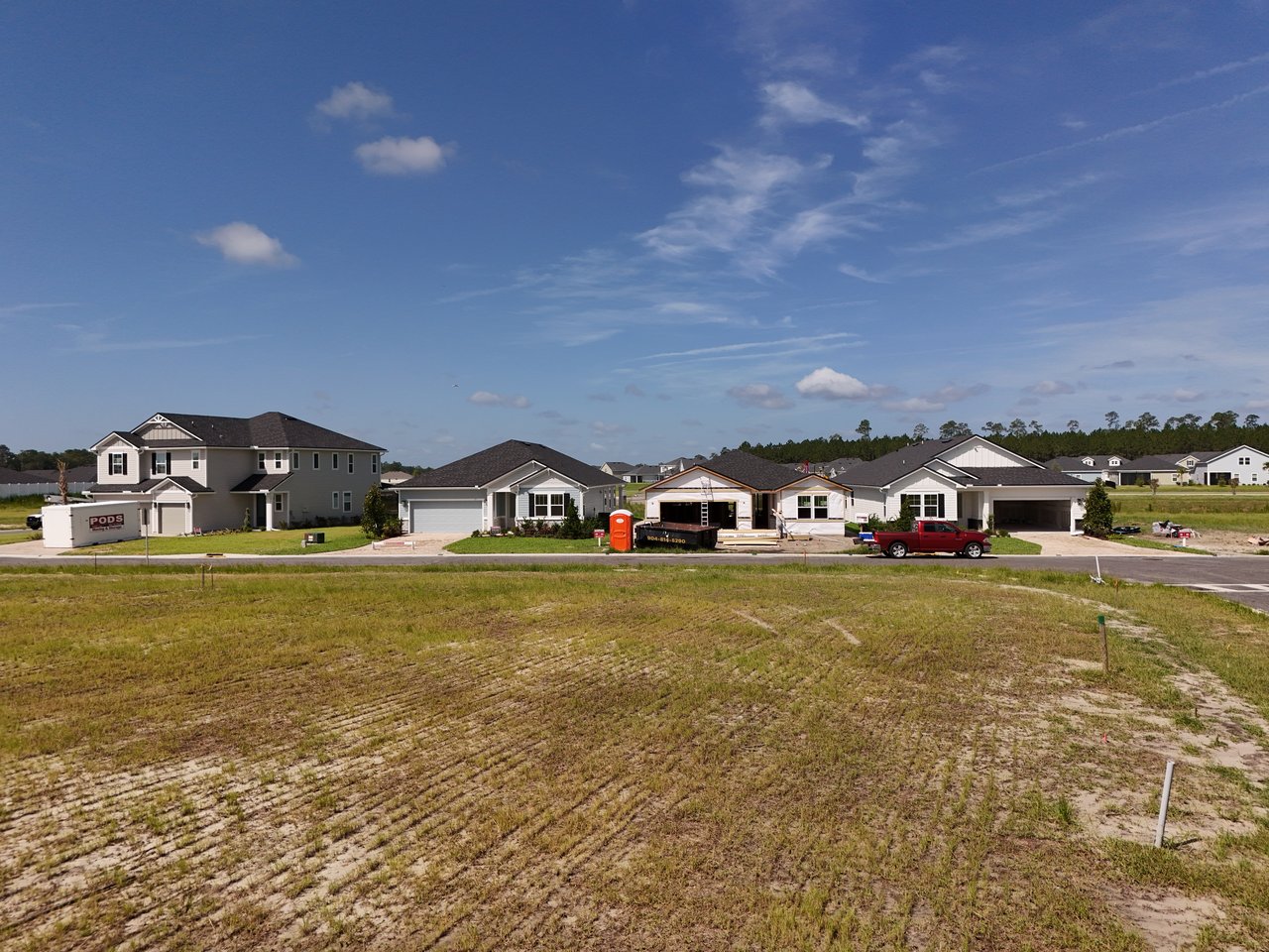 New homes along a residential street, including one under construction, with a graded lot in front.
