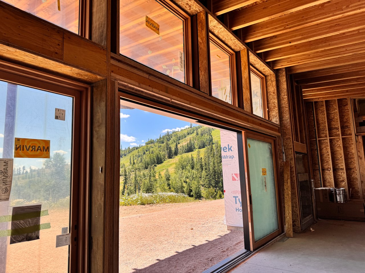 Inside look at a luxury mountain home under construction featuring massive floor-to-ceiling Marvin panoramic windows.
