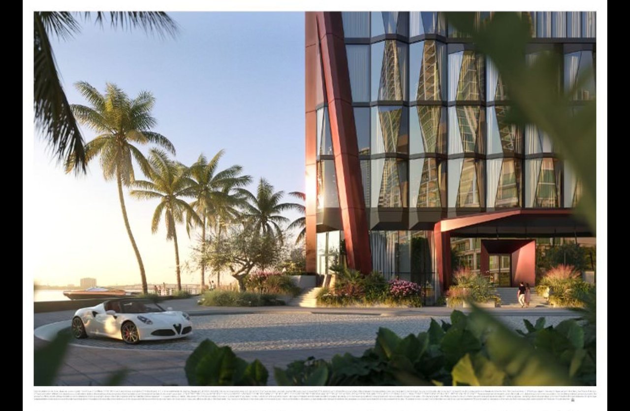 Modern glass high-rise with red angular facade, palm trees, and a white sports car at the entrance.