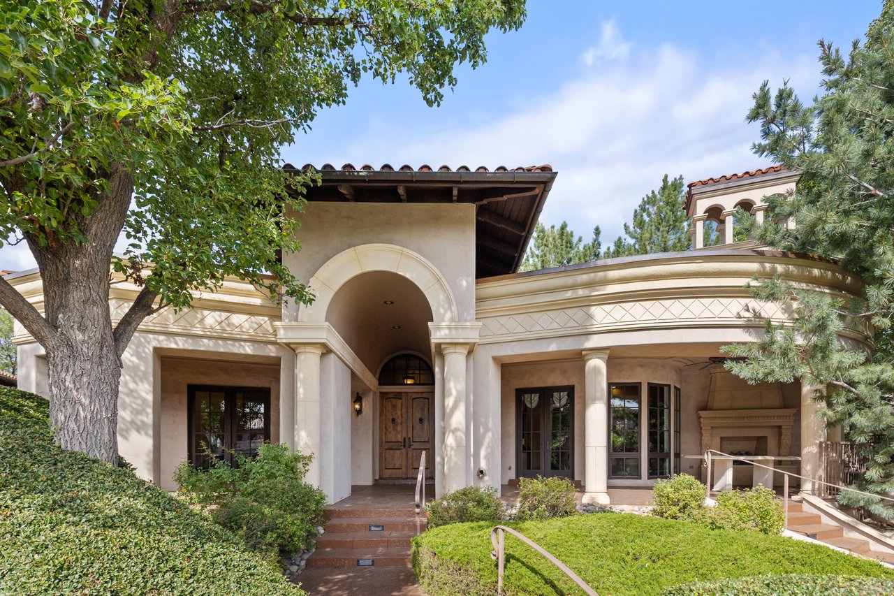 Guest house with an arched entry, landscaped grounds, and a covered patio with an outdoor fireplace.