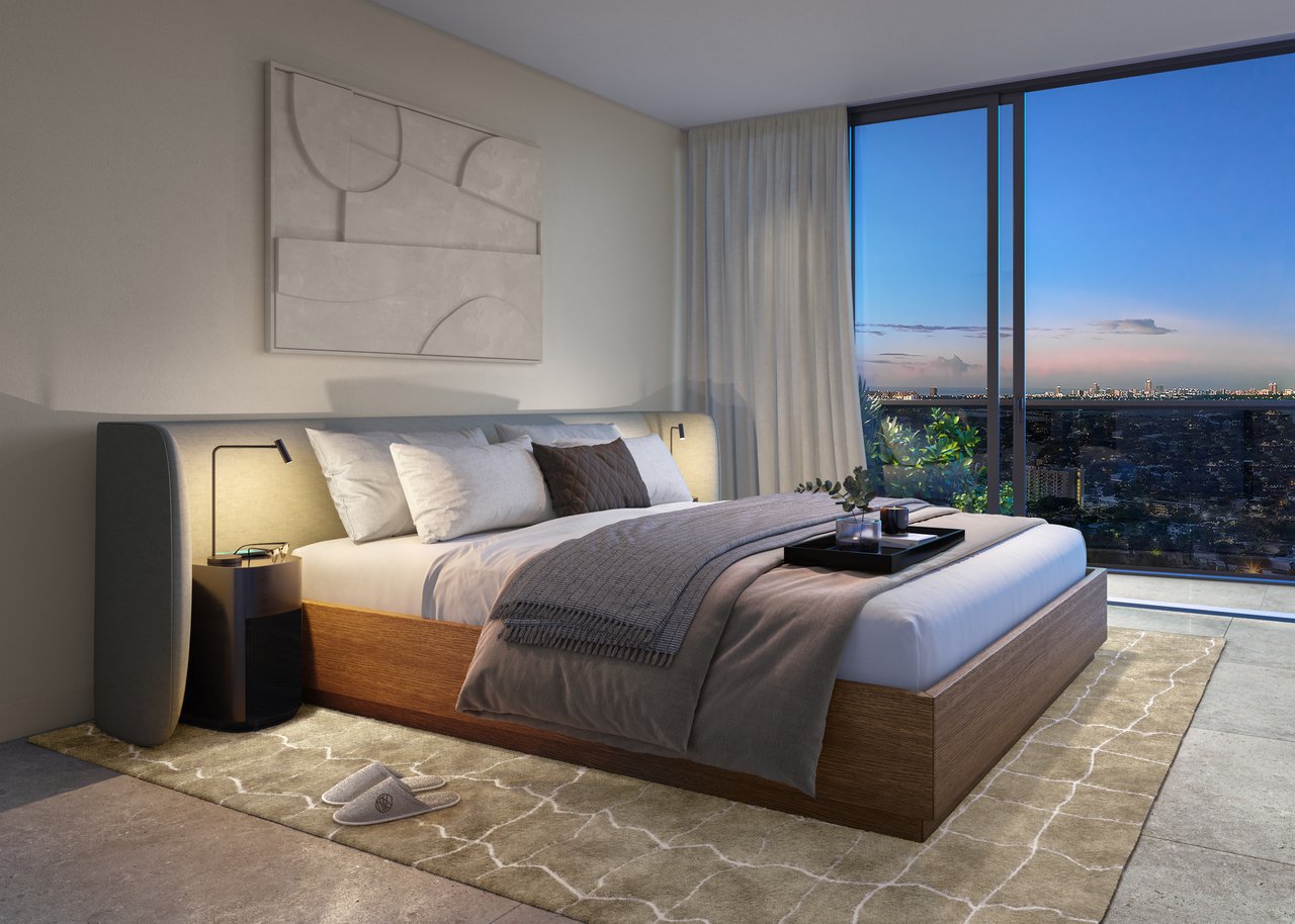 Modern bedroom with a low wood-framed bed and floor-to-ceiling windows overlooking the city at dusk.