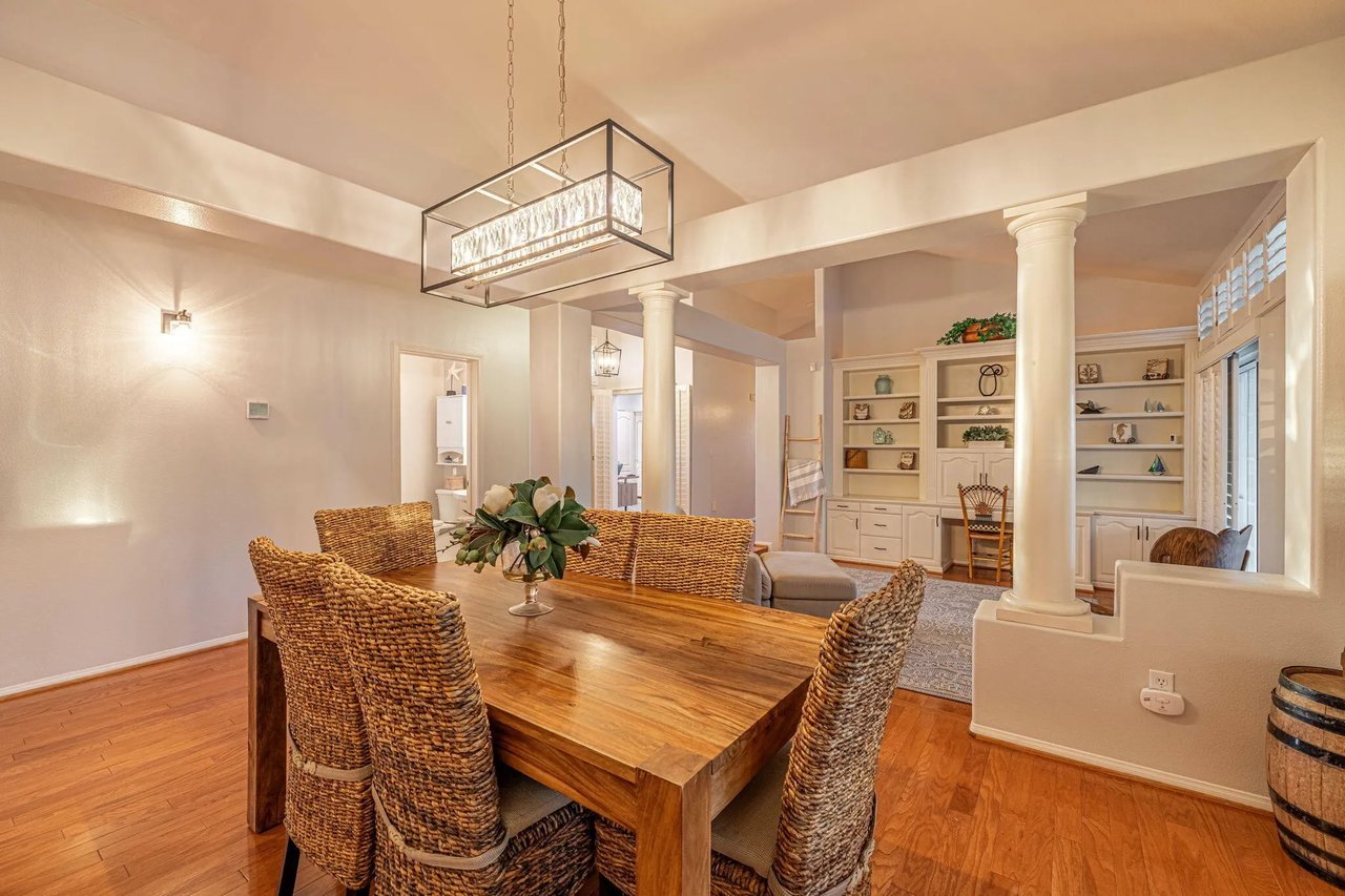 Dining room with a rustic wood table, wicker chairs, and built-in shelving.