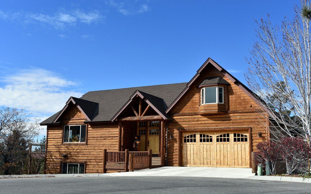 Log-style house in Rifle with a covered porch, wooden garage door, and paved driveway.
