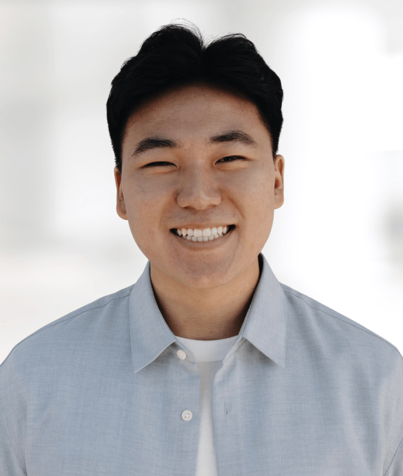 Jason Lee smiling in a light blue collared shirt.