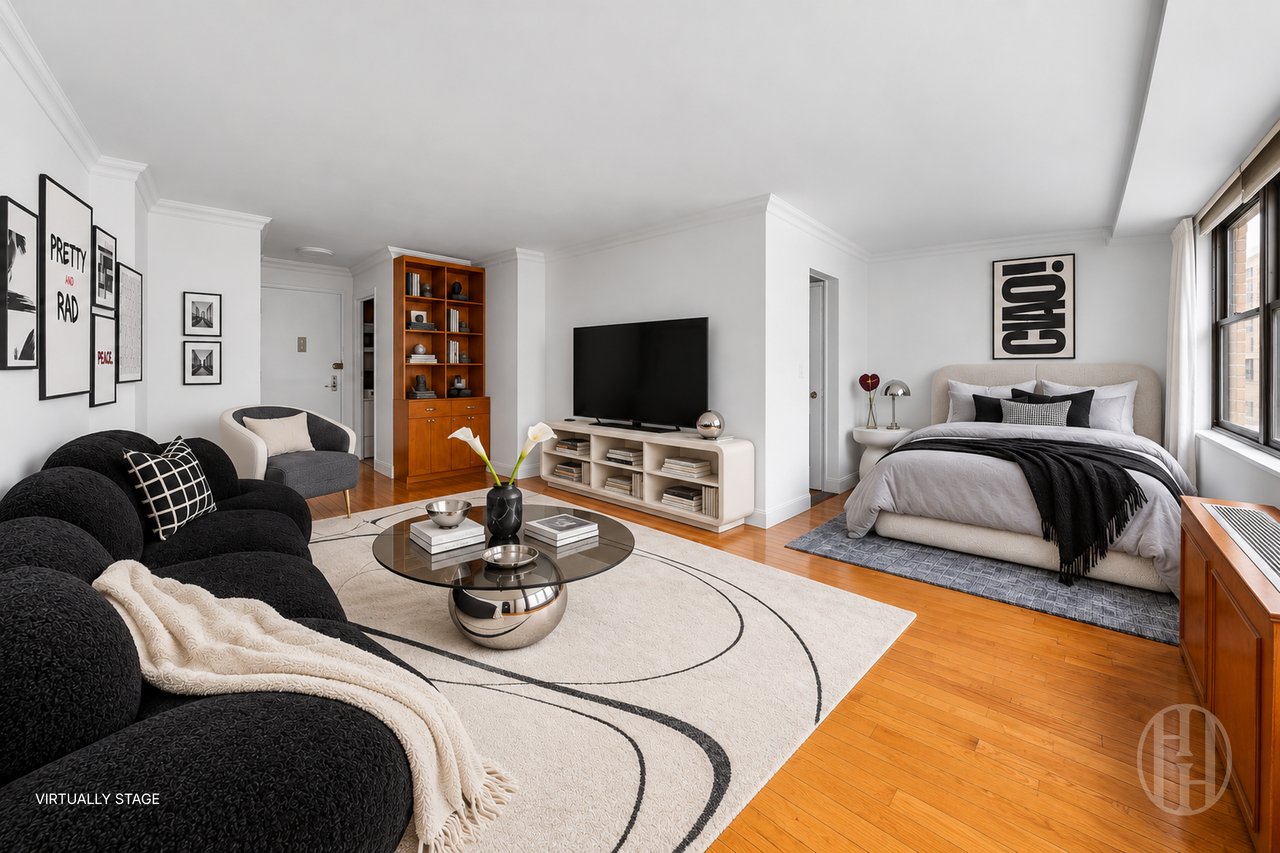 Virtually staged studio living area and bedroom with a black sectional, glass coffee table, and large windows.