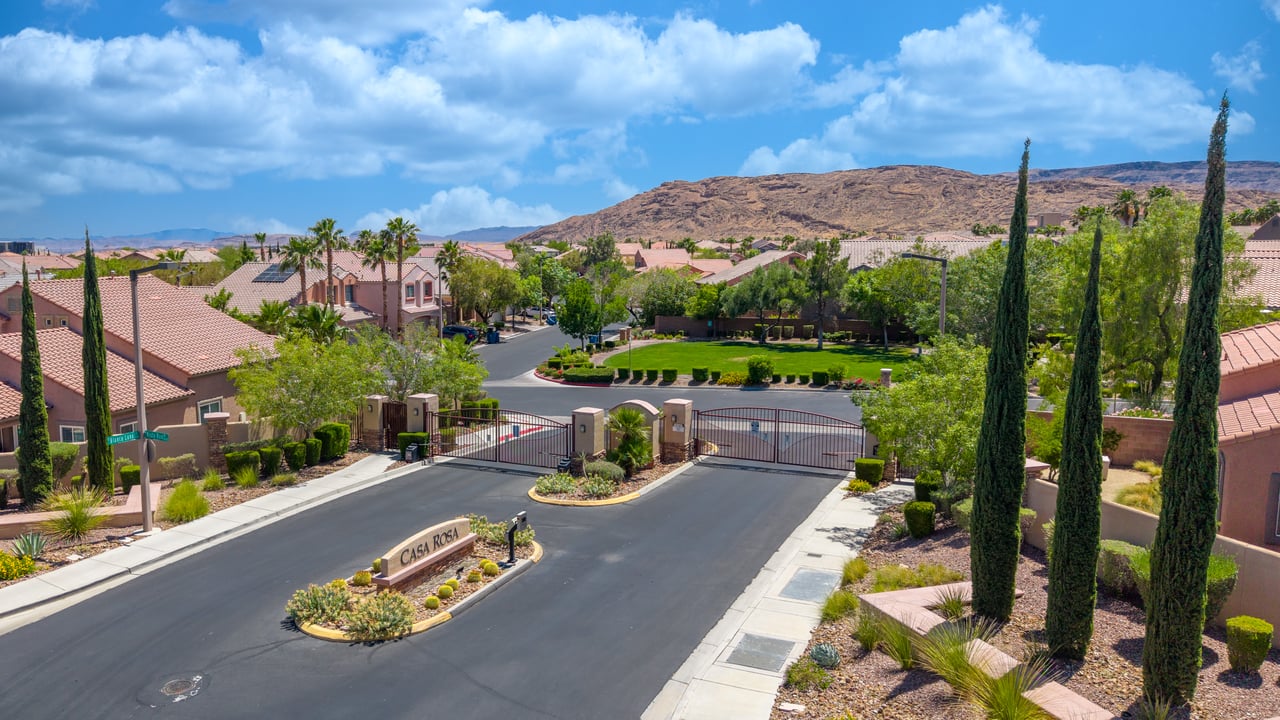 Gated Casa Rosa community entrance with landscaped roadway and desert hills beyond.