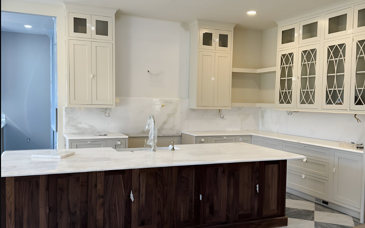 Renovated kitchen with cream cabinets, marble surfaces, and a large dark wood island.
