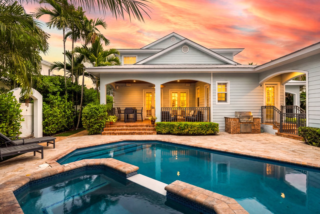 House exterior with a swimming pool, covered patio, and sunset sky.