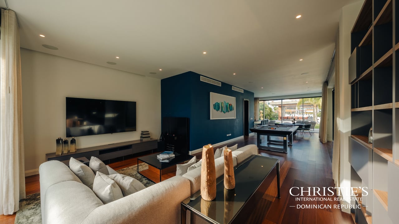 Living room with a white sectional, blue accent wall, pool table, and sliding doors to a patio.