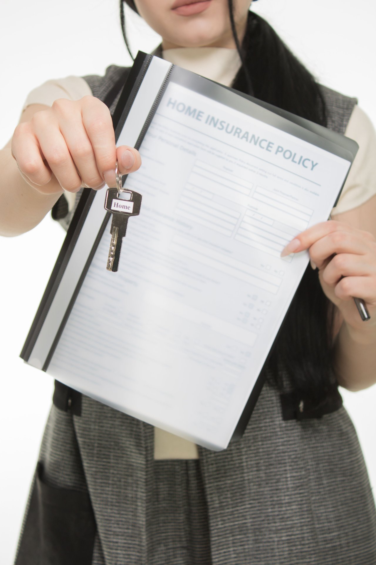 Woman holding a house key and a clipboard labeled Home Insurance Policy.