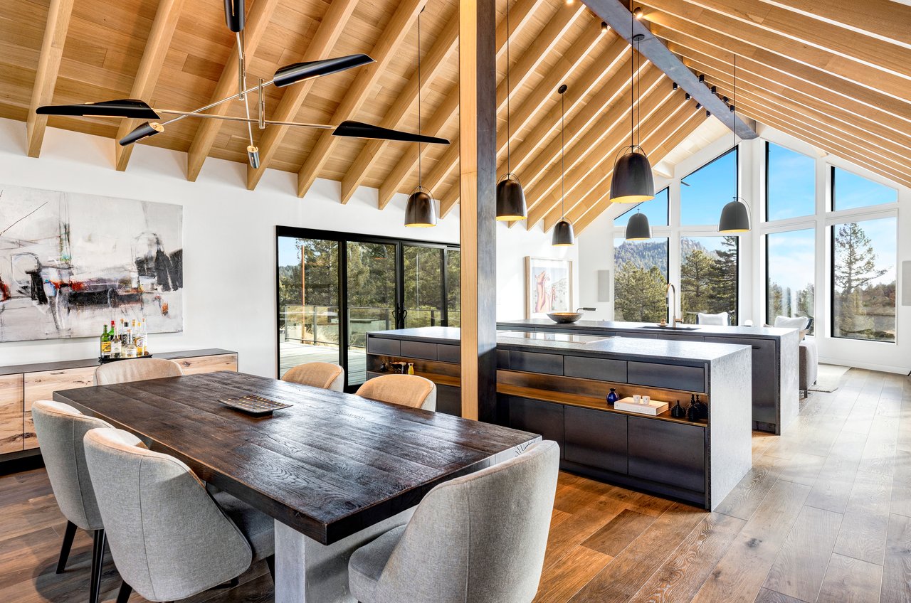 Open-concept Boulder dining area and kitchen with black accents, exposed wooden beams, and mountain views through large windows