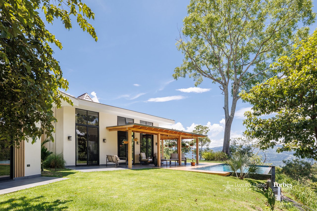 Modern white home with timber pergola, infinity pool, and distant valley views.